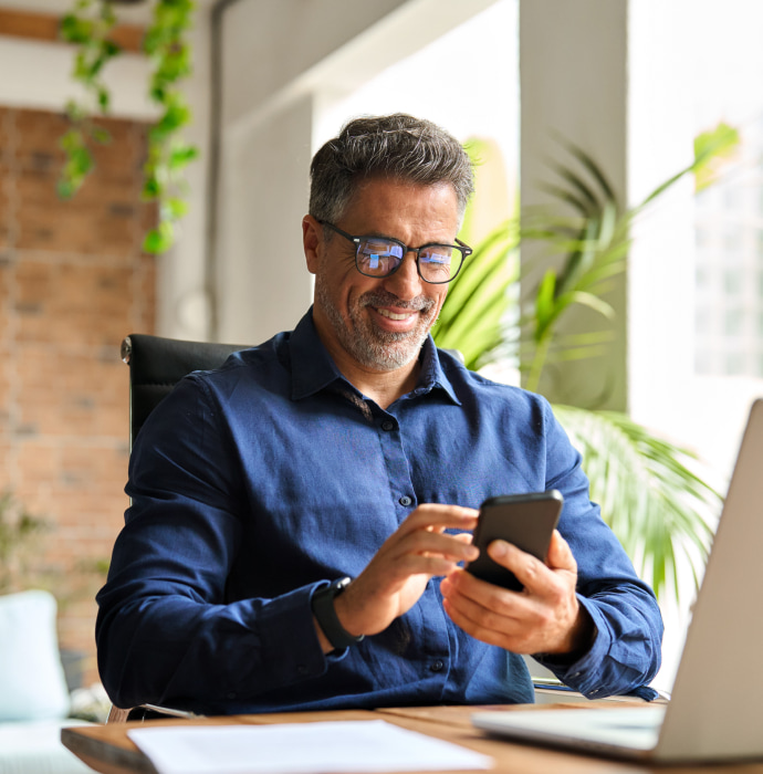 Man sitting at desk looking at phone